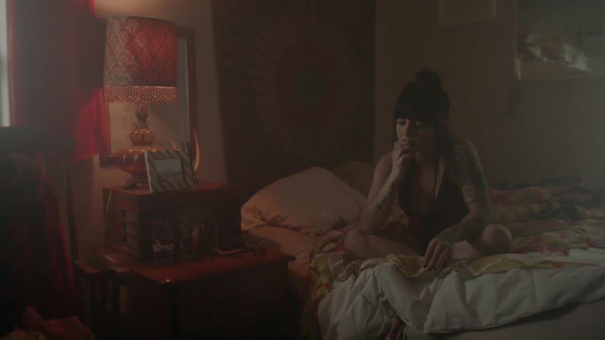 Woman sits on her bed thinking