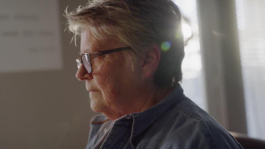 A woman wearing glasses looks downward