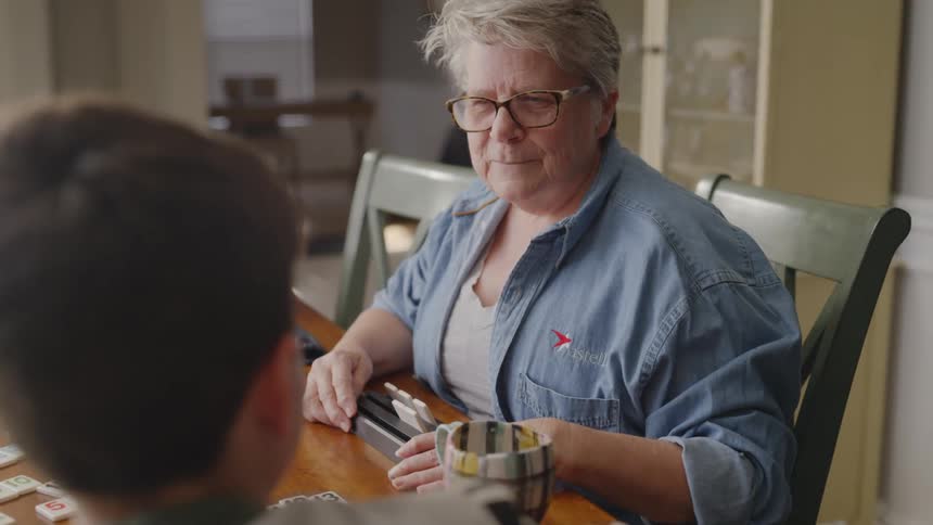 An older woman and a younger boy are playing a game at the kitchen table