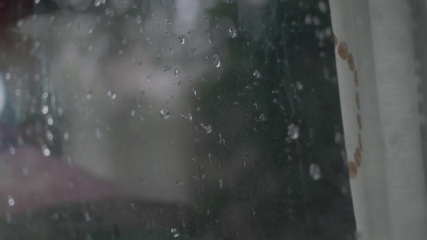 Raindrops roll down a window pane