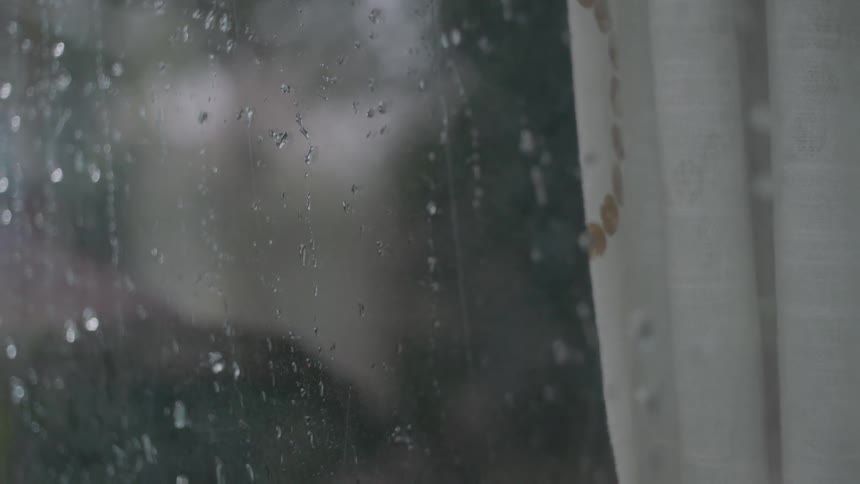 Rain drips down a glass window