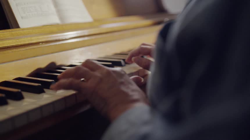 Sunlight shines on a piano and music book as a person plays