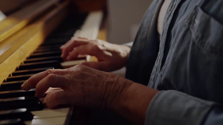 Elderly woman practices a piano