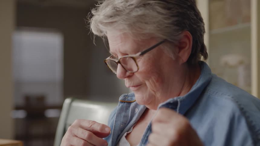 Elderly woman studies a table game and talks with someone
