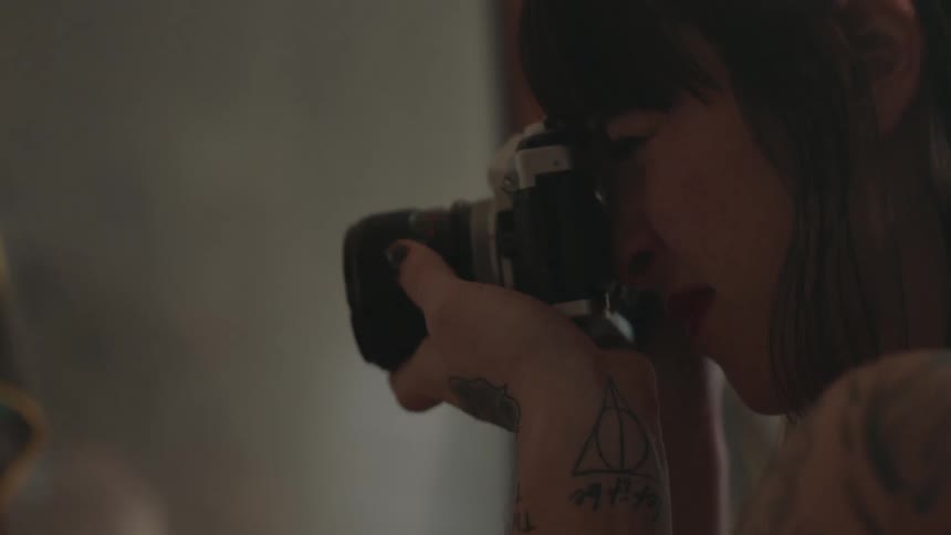 A woman is taking a picture of something with an old film camera