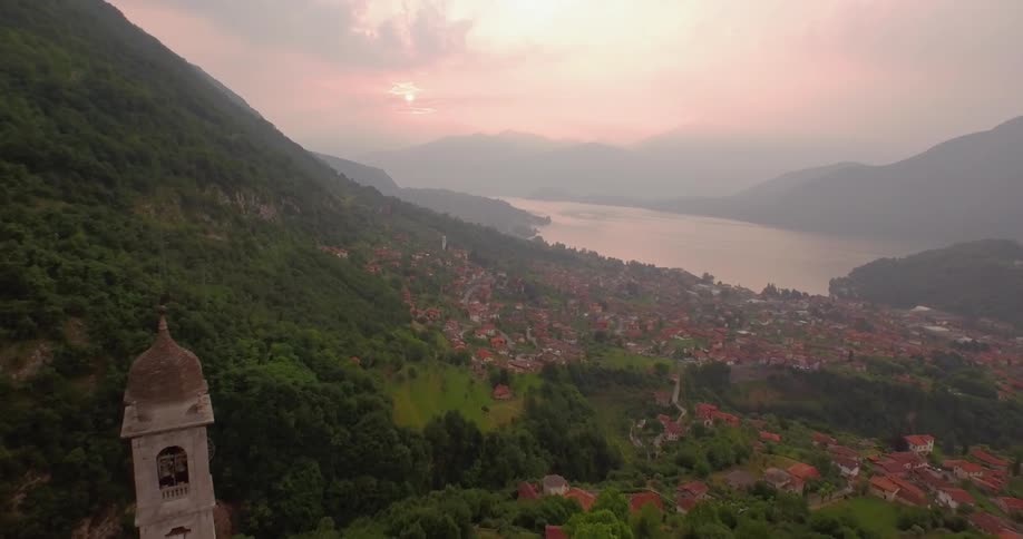 The sun sets over a mountain town and lake