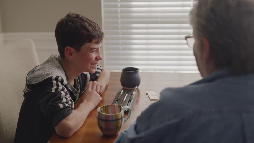 Elderly woman plays a table game with a boy