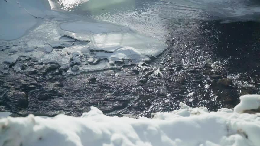 Water flows down a stream with ice