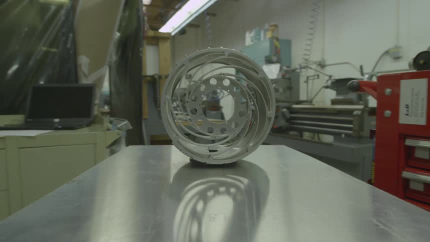 Tray rolling through a workshop with a circular metal object on top