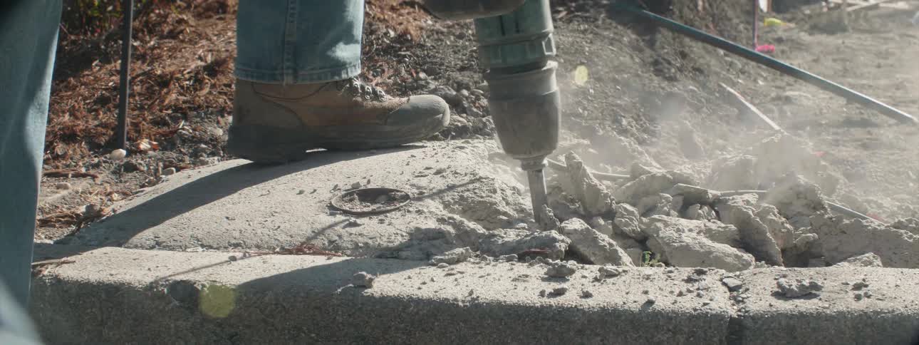 A person is cutting through the concrete with a jackhammer