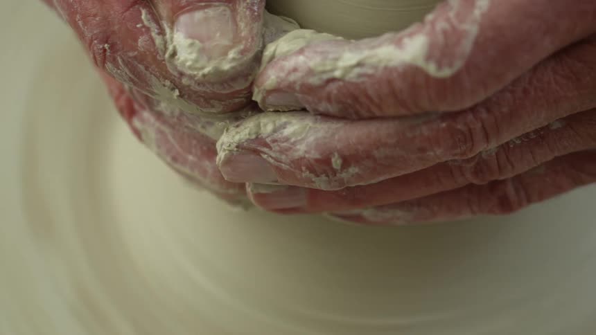 Man molding pottery in a spinning pottery wheel