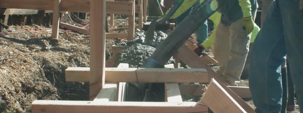 People are working together pouring and shaping concrete