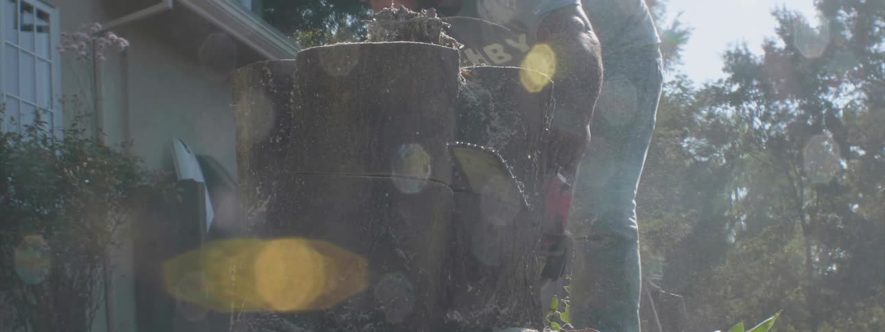 A man cuts down a tree trunk with a chainsaw