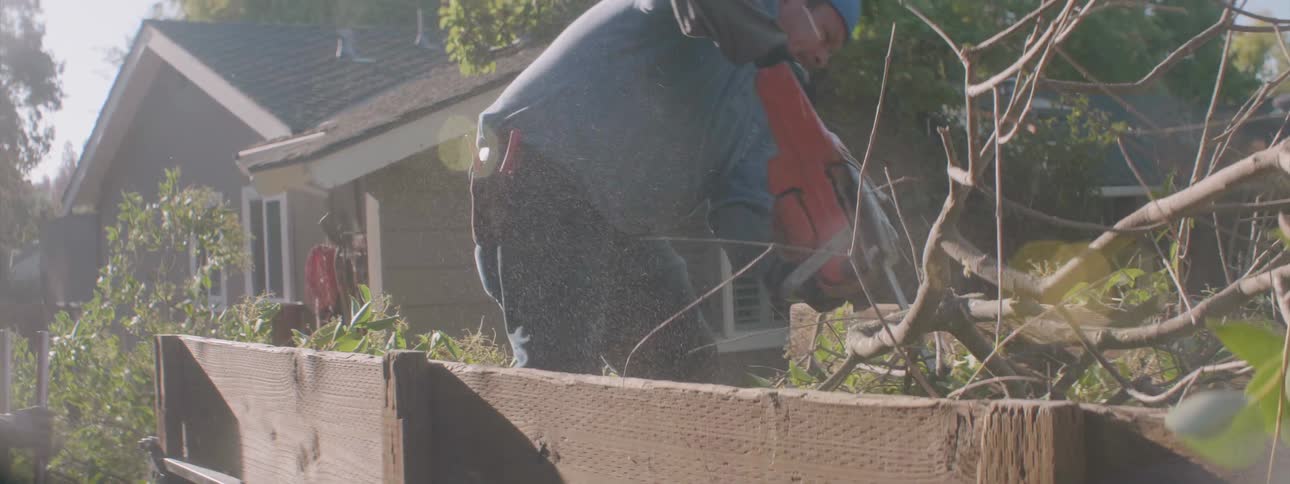 A man cuts tree branches with a chainsaw