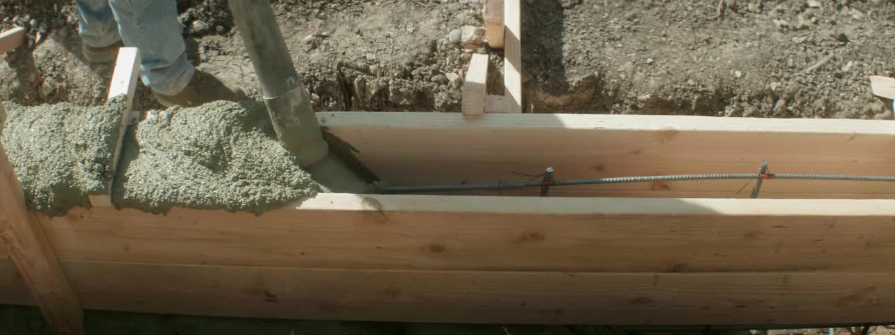 A person is filling a crevice with concrete from a hose