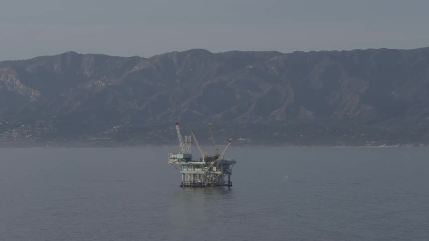View of an oil rig in the middle of the water on a hazy day