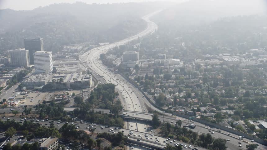 The fog is rolling in over the highway and city