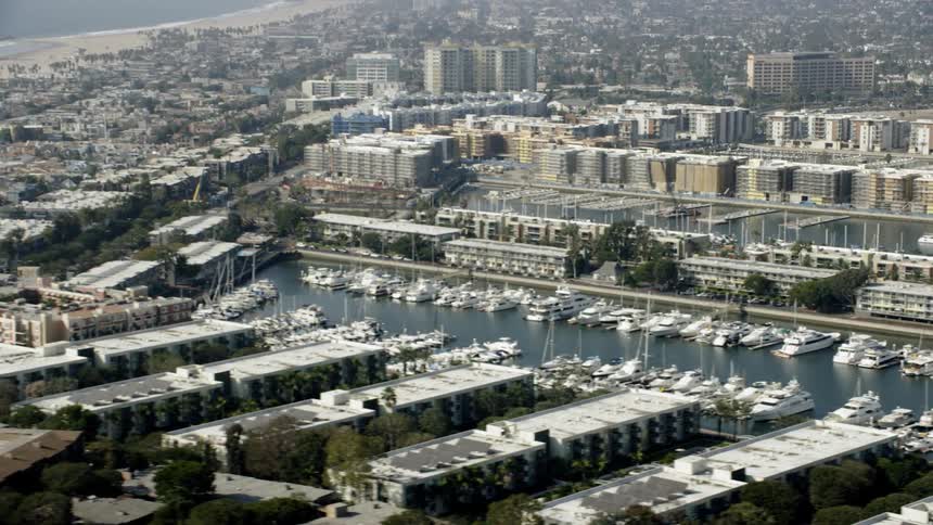 A large city with a beach in the distance is filmed from above
