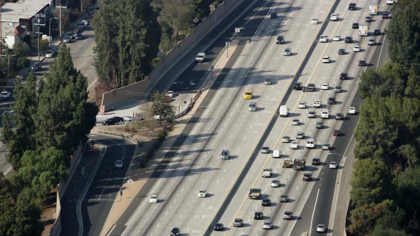 Cars travel on a highway and city streets