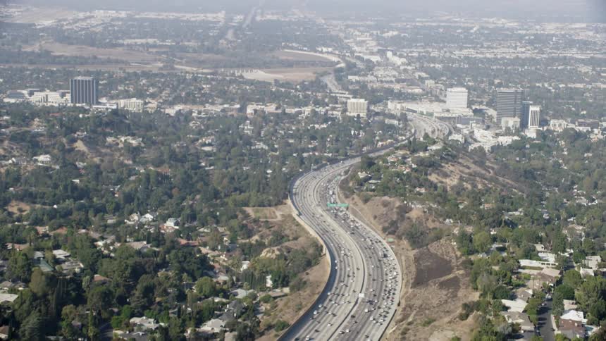 Cars traveling down a tree lined highway