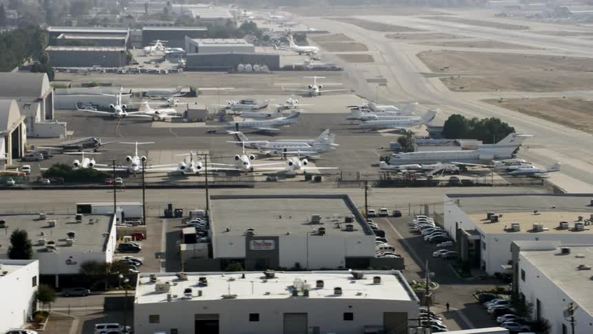 Airplanes are sitting waiting near a hangar at an airport during the day