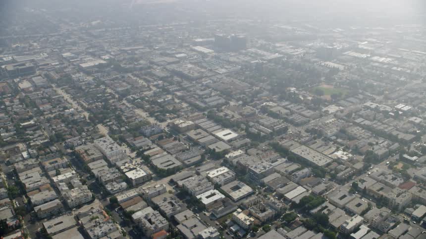 Smog is hanging in the air over an area of urban sprawl during the day