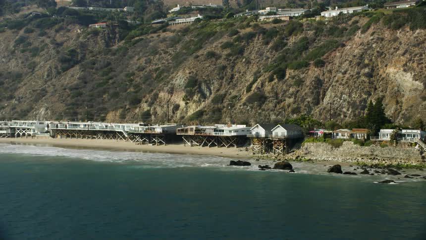 Houses sit on stilts on a beach