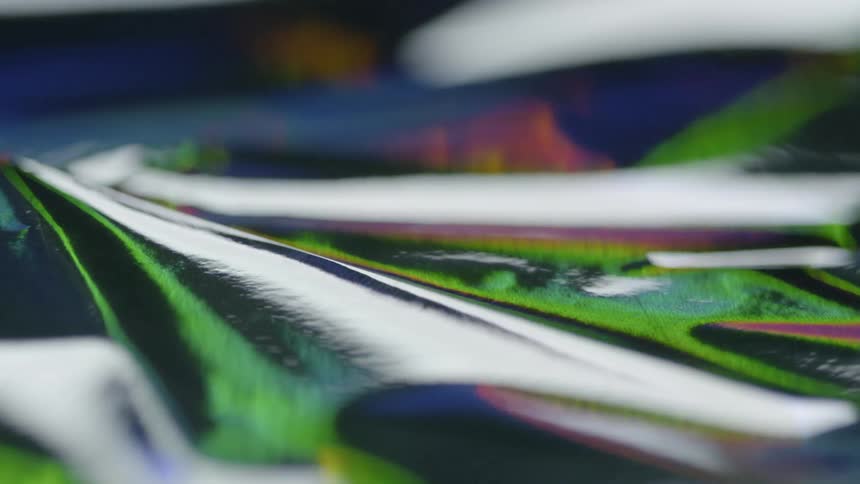 Light, color, and shadow are moving across a reflective surface