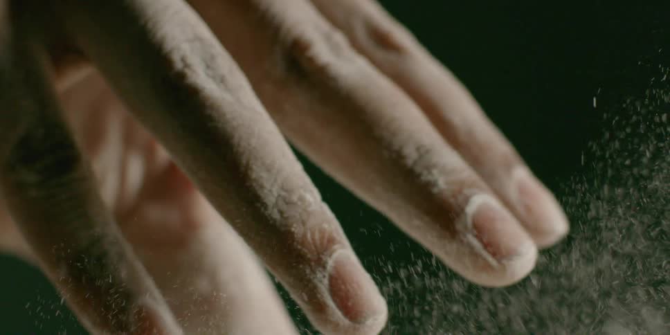 A chef sprinkles flour from their fingertips