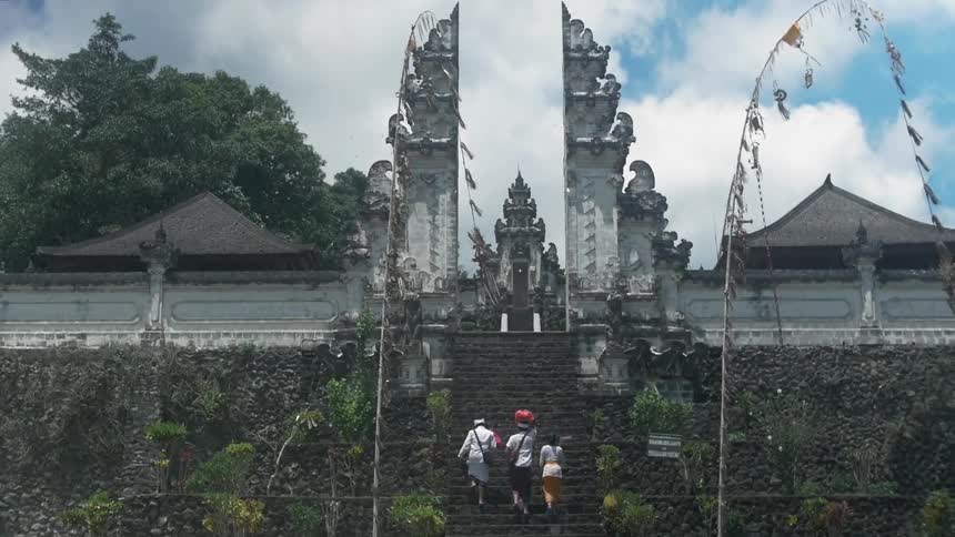 Some people are walking up the stairs to an old temple