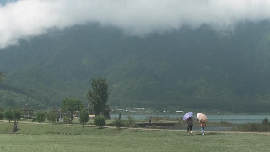 Two people walk with umbrellas on a sunny day