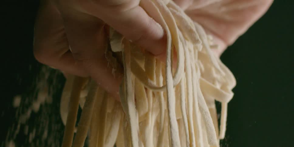 A chef holds raw pasta