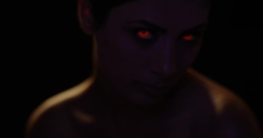 A woman with orange glowing eyes looks up