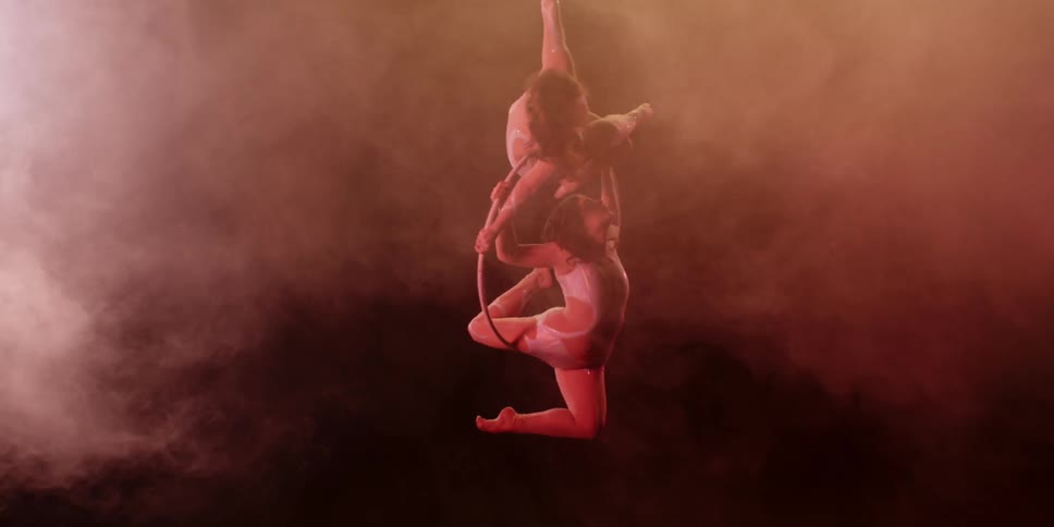Two people are dangling from a circle performing a routine