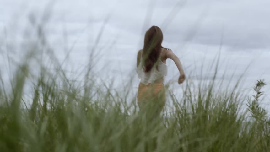 A woman runs in the tall grass