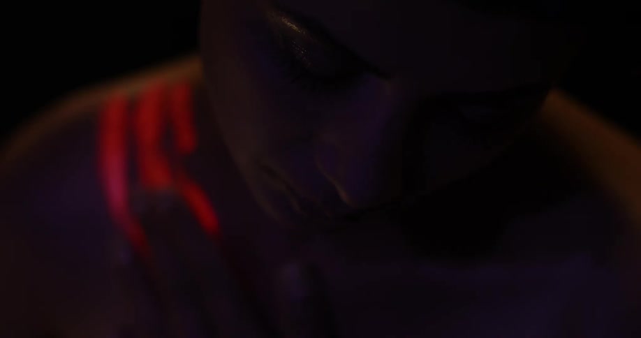 Someone is rubbing glow paint on themselves in a dark room
