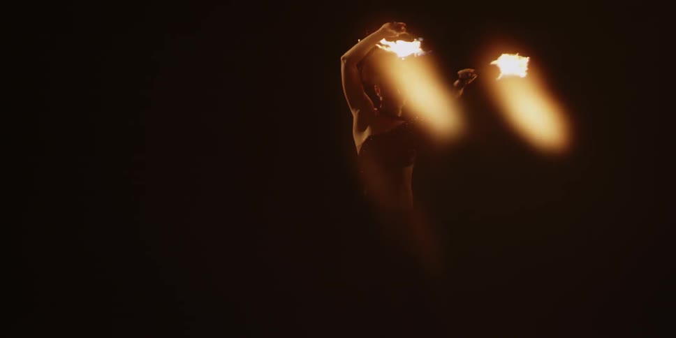 A woman is twirling two torches as she performs