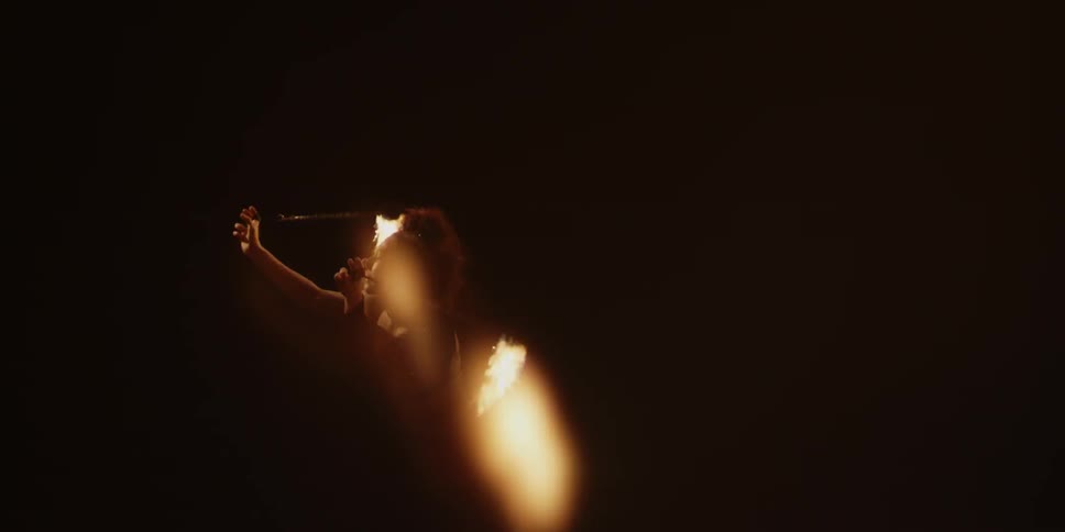 A performer spins balls of fire on chains