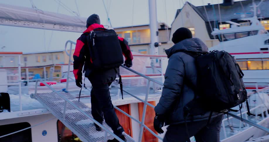 Two men board a ship on a snowy day