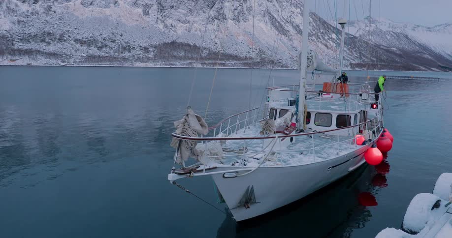 People stand on a boat floating off the snow covered coast