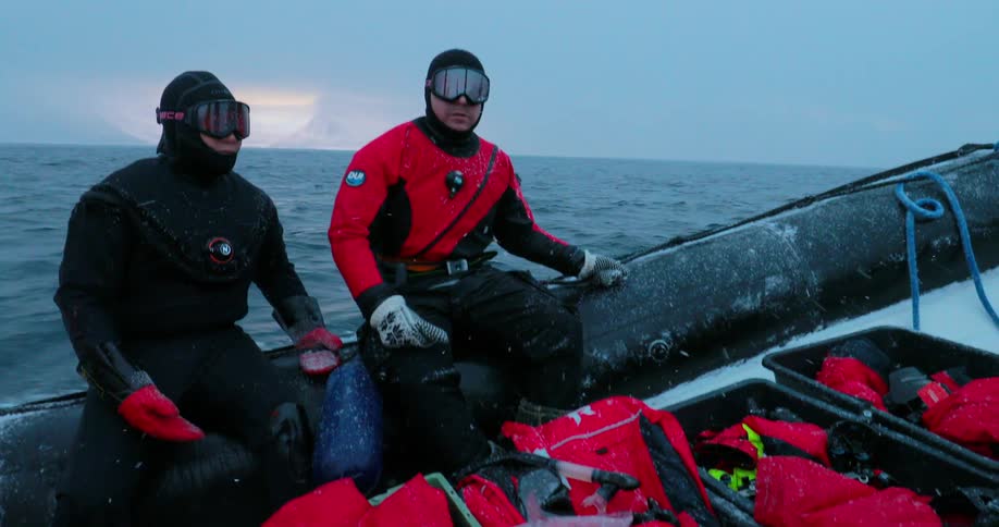 Two divers ride in a raft while it snows
