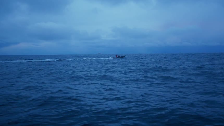 People are riding in a boat as it speeds across the ocean at dusk
