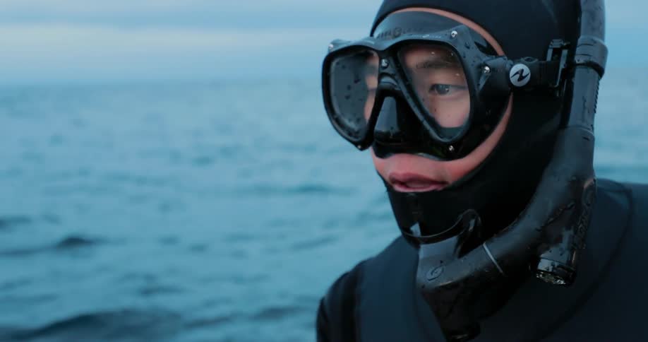 A man is sitting on a boat wearing diving gear during the day