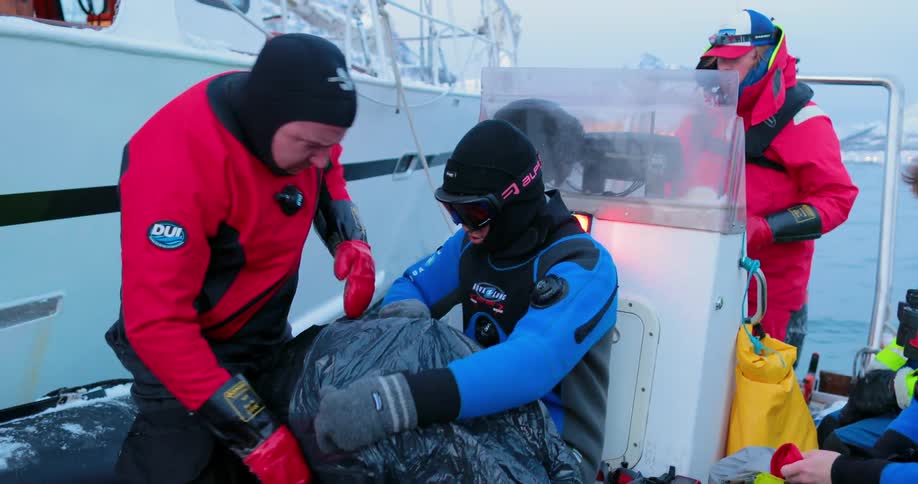 People gathering and adjusting gear on a small boat in a very cold area