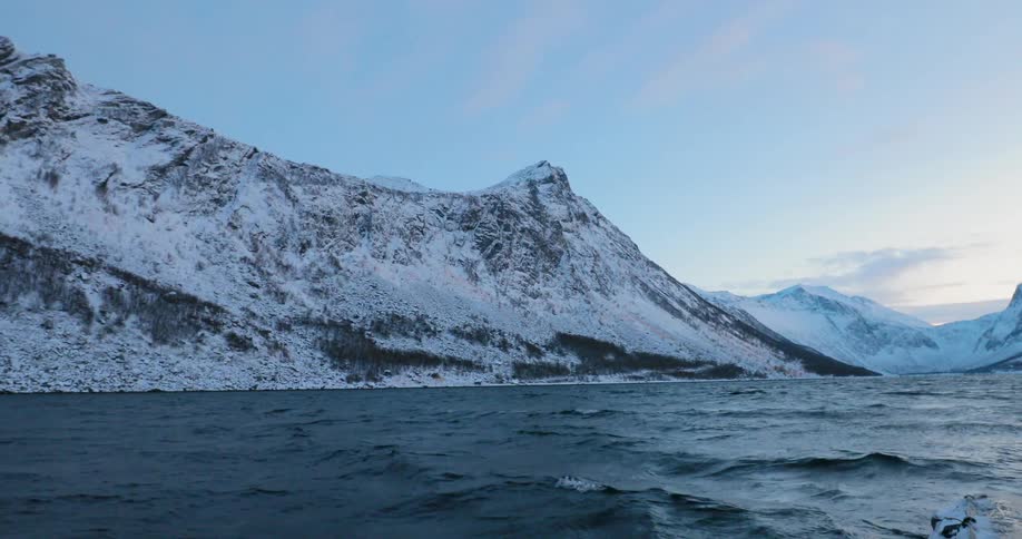 Snow and ice cover the mountains next to choppy waters