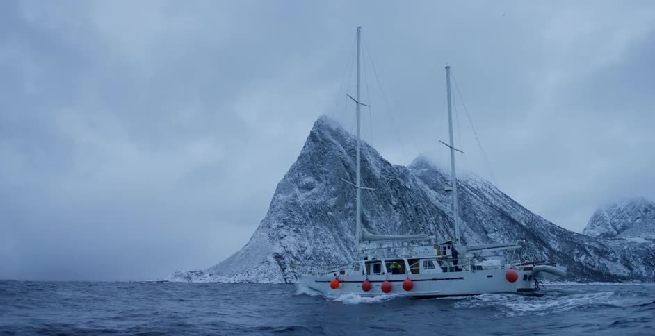 A boat travels through the ocean on a cloudy winter day