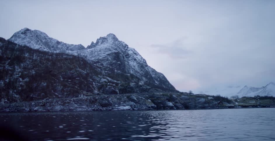 Clouds are hovering in the sky along a snow-covered coast at dawn