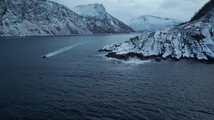 Boat moving quickly between large rock formations on a cloudy day