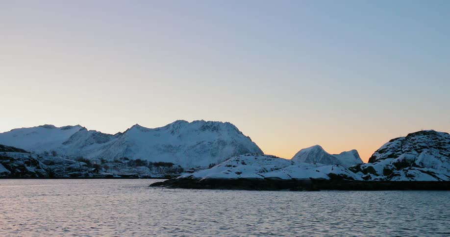 Snow covers the hills and mountains bordering the water