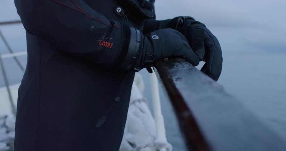 A man in diving gear is leaning against a ship's railing